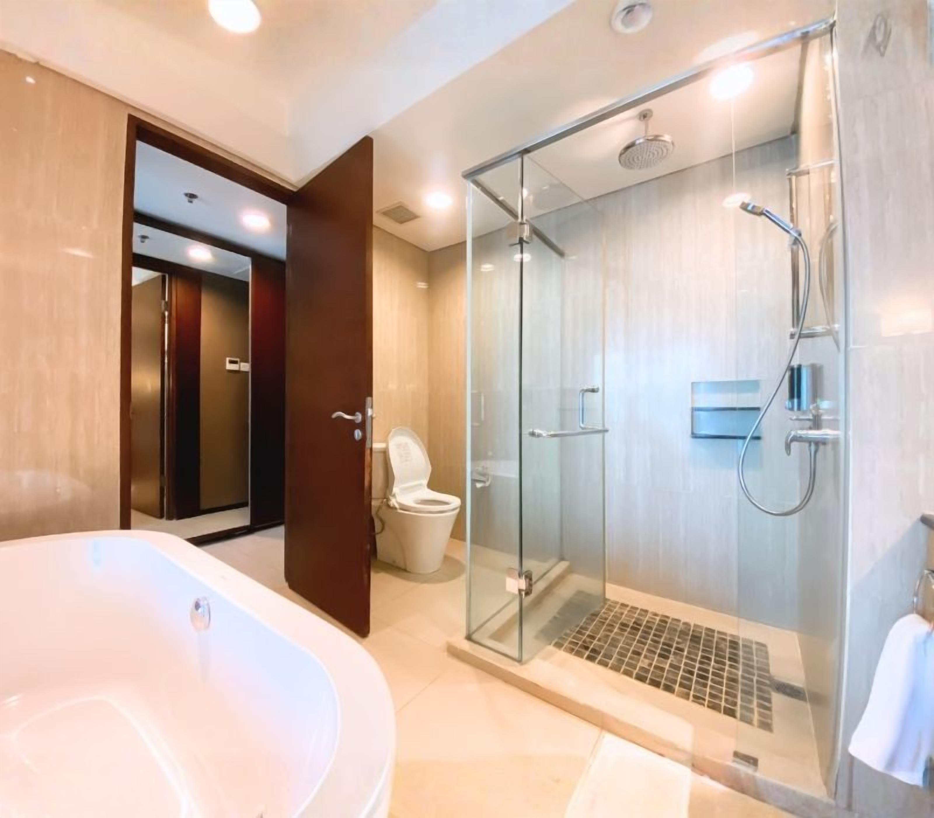A modern bathroom with a glass-enclosed shower, a standalone bathtub, and a toilet.