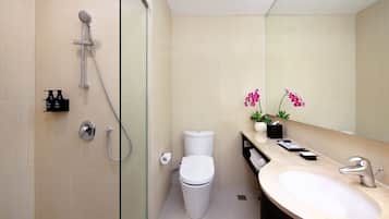 A modern bathroom with a glass-enclosed shower, a toilet, and a sink with a mirror.