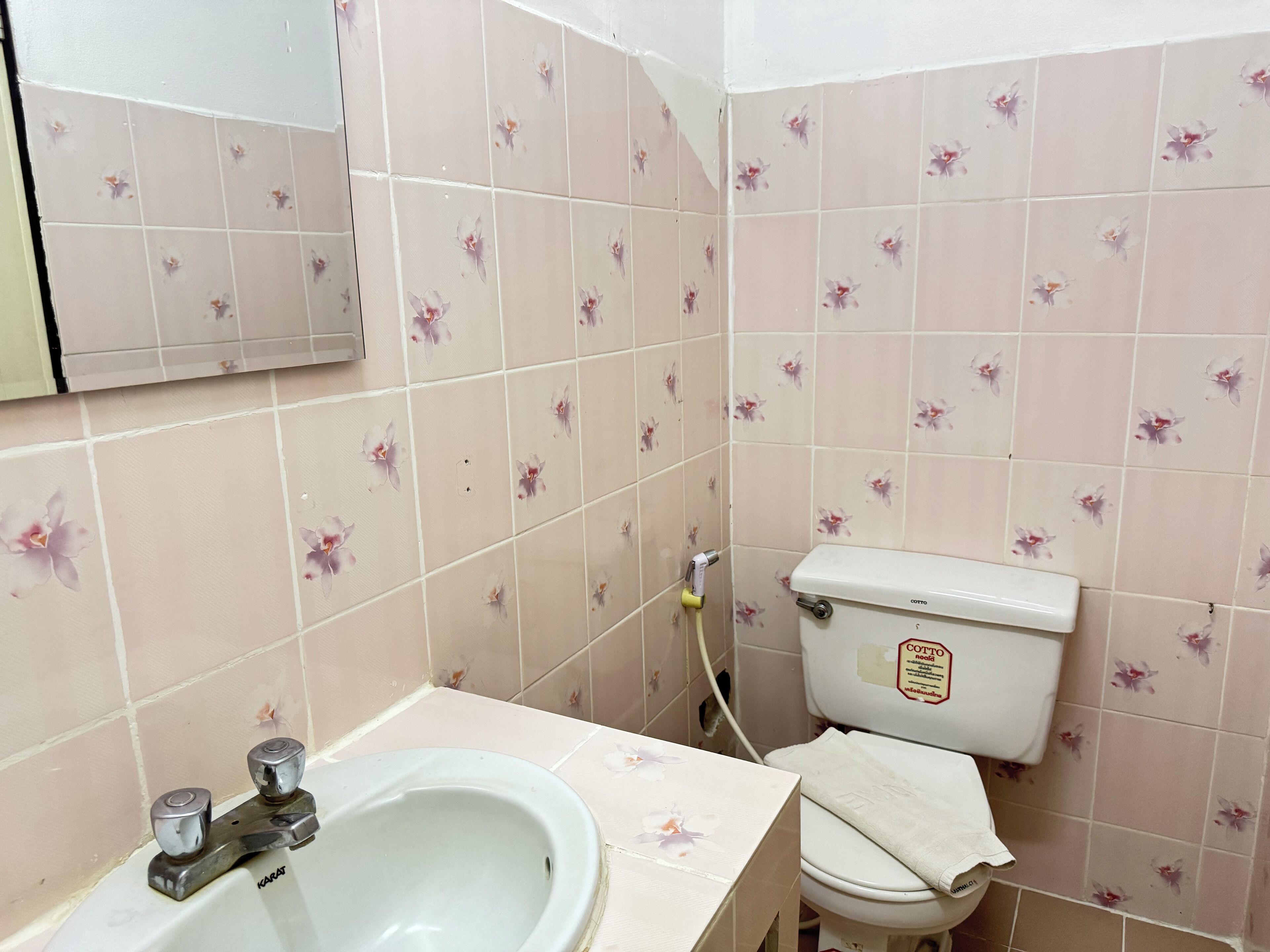 A bathroom with floral-patterned tiles, a white sink, and a toilet.