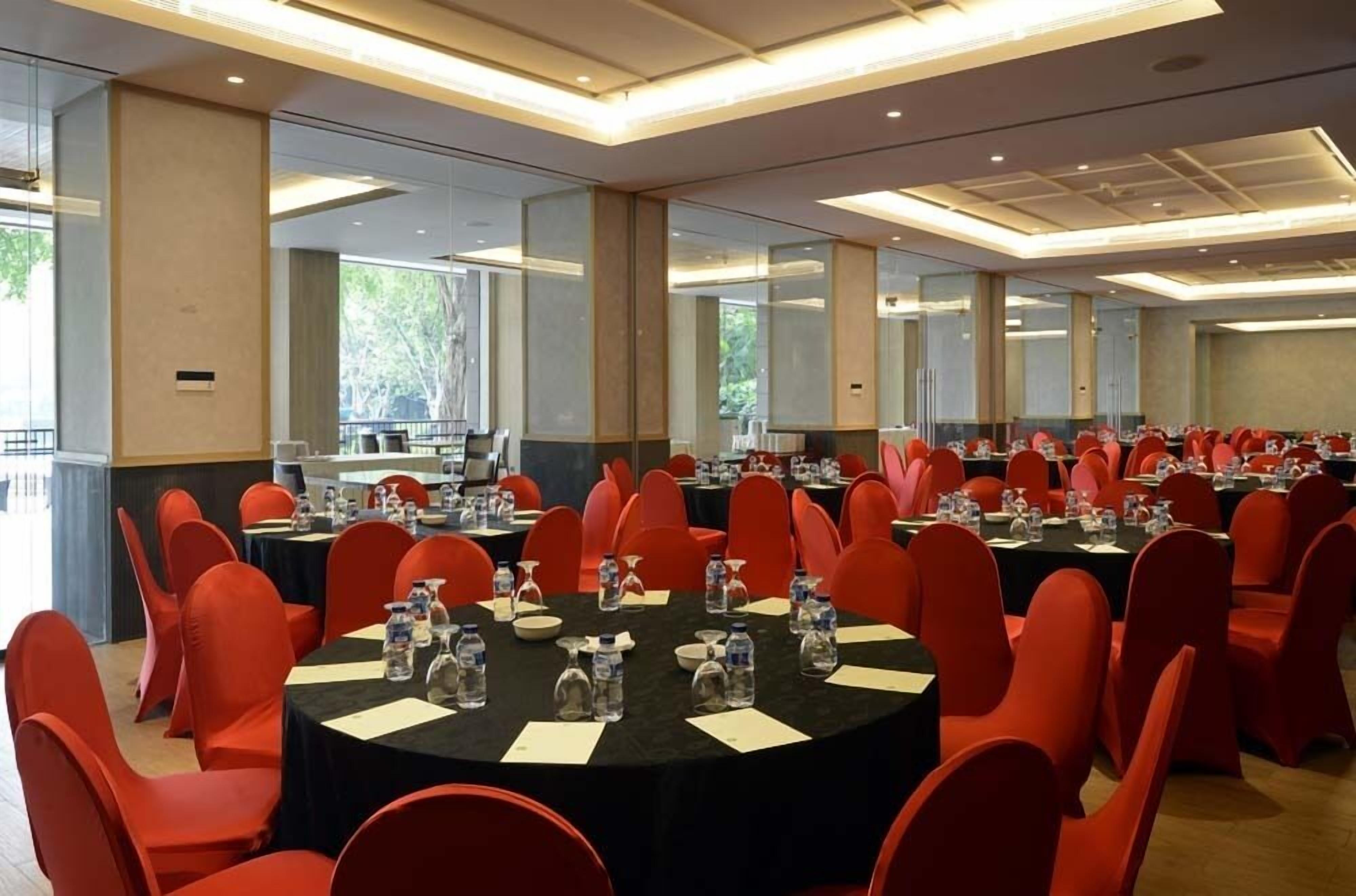 A conference room with round tables, red chairs, and water bottles.