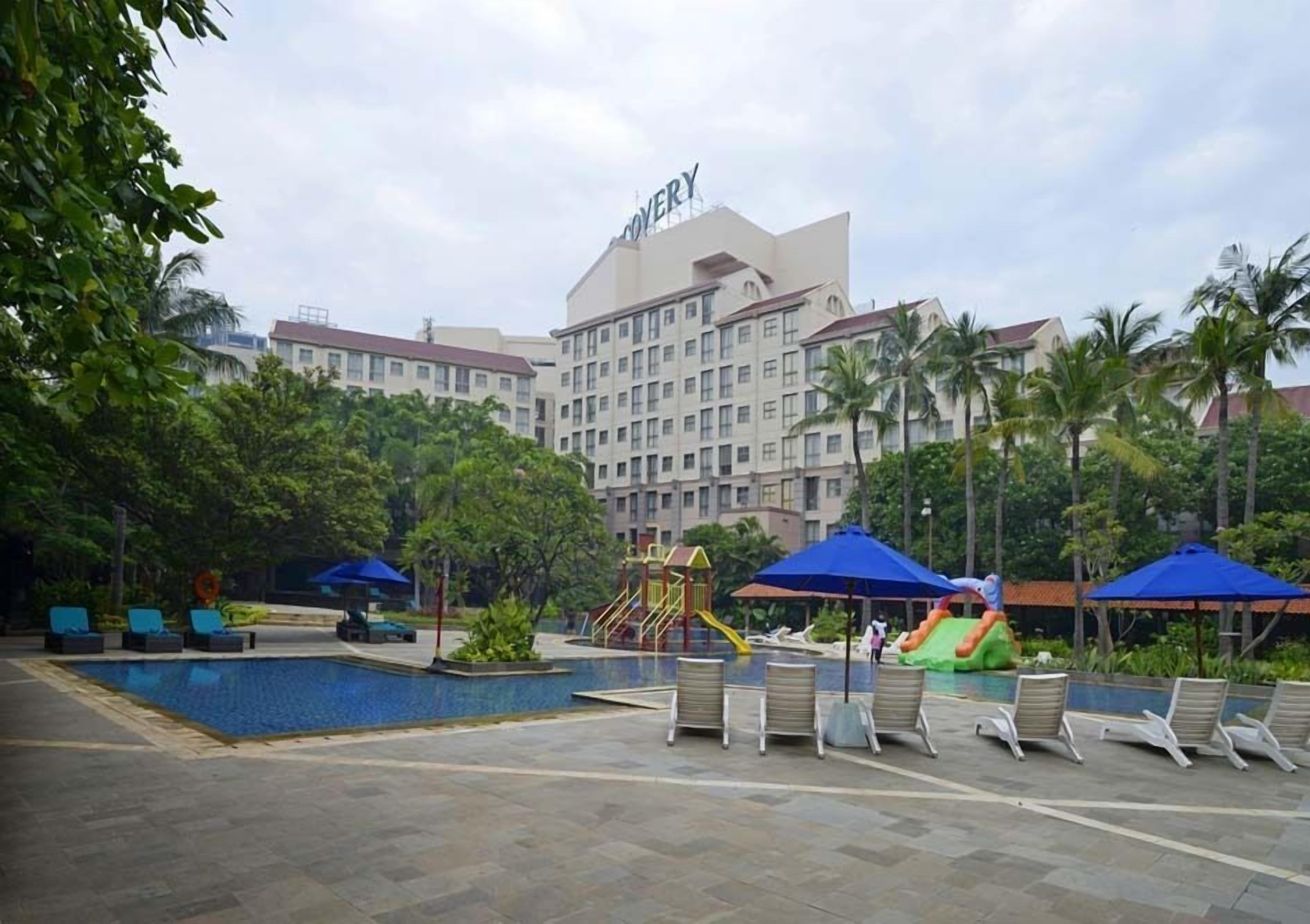 Ein Hotel mit Schwimmbad, Liegestühlen und einem Spielbereich für Kinder.