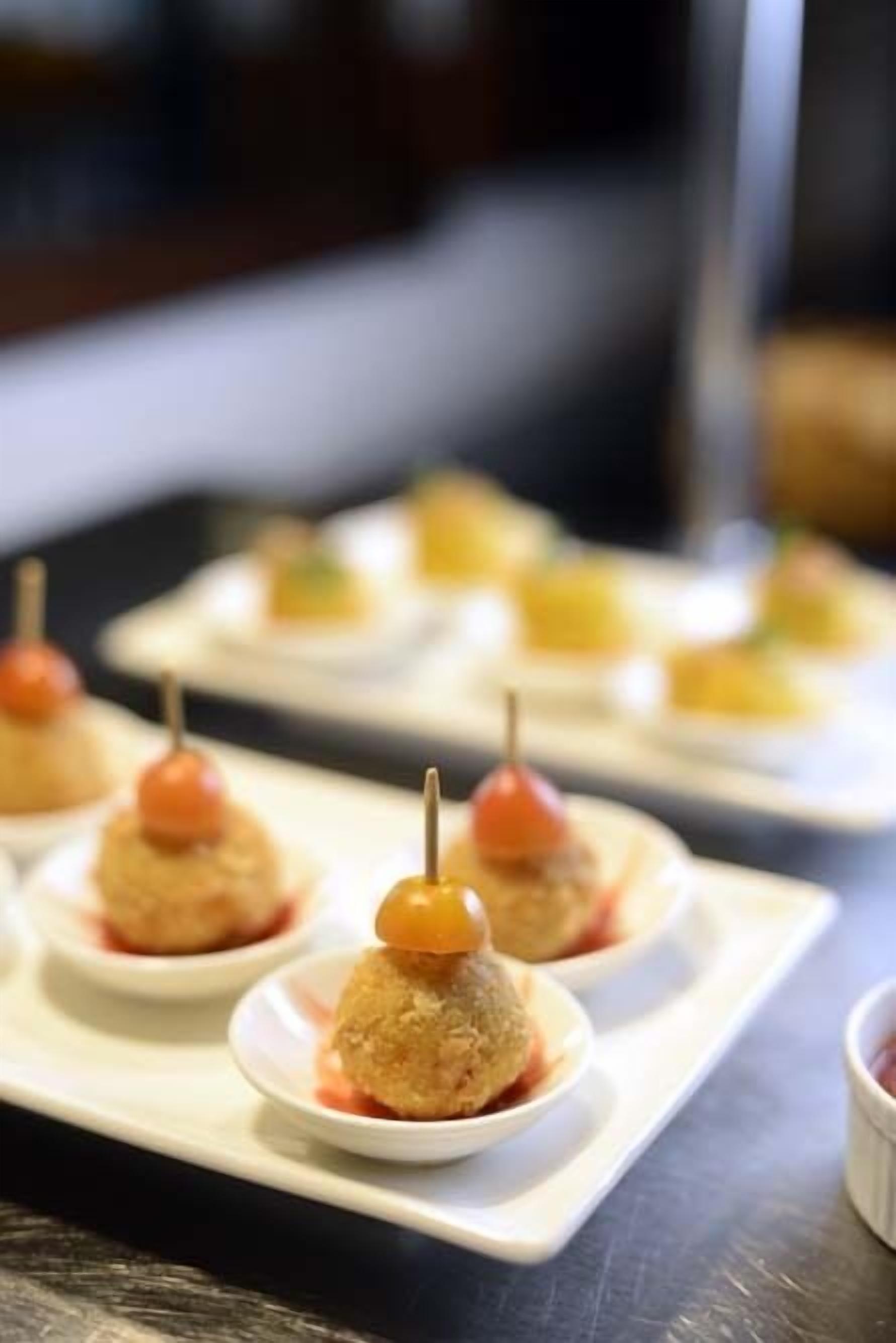 Una bandeja de aperitivos con brochetas, dispuesta sobre un plato blanco.