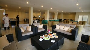 A spacious lounge area with wicker furniture, a pool table, and a buffet table with various dishes.