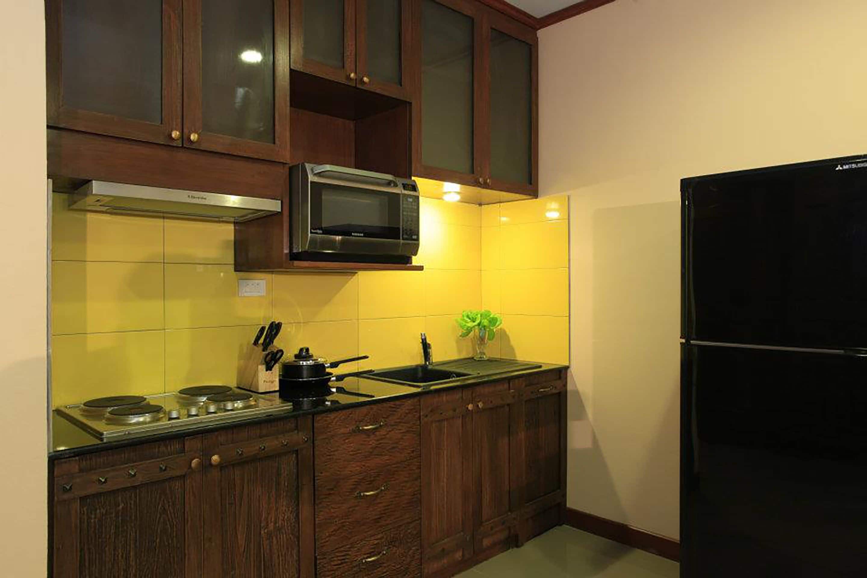 A kitchen with wooden cabinets, a microwave, a stove, and a black refrigerator.