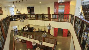 Um saguão de hotel em vários níveis, com uma escadaria central, um mezanino com assentos e vista para o elevador.