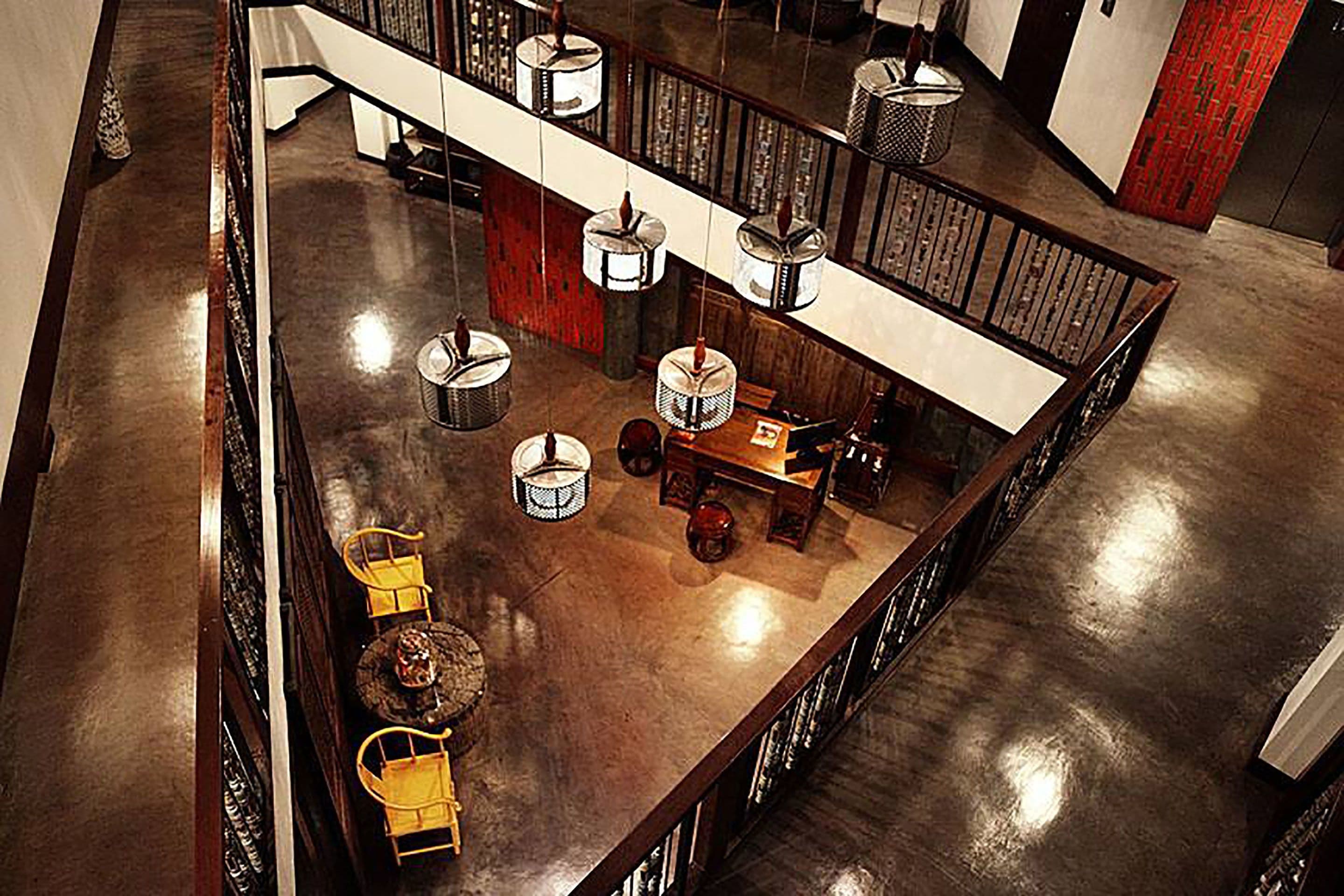 A spacious, modern lounge area with a high ceiling, multiple seating arrangements, and a central table.