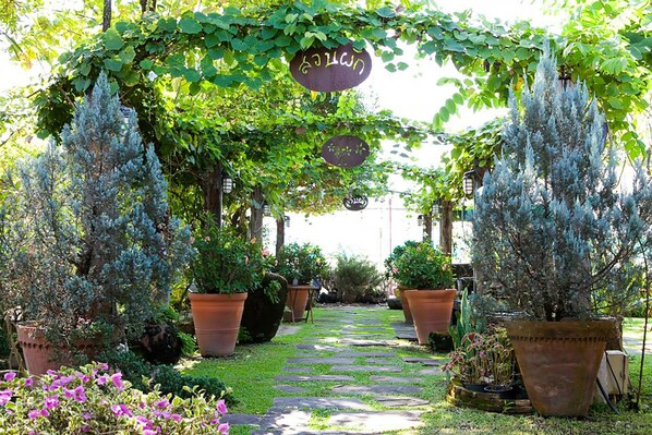 A garden pathway with potted plants and hanging signs.
