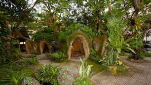 A lush garden with stone archways, a small pond, and various plants.