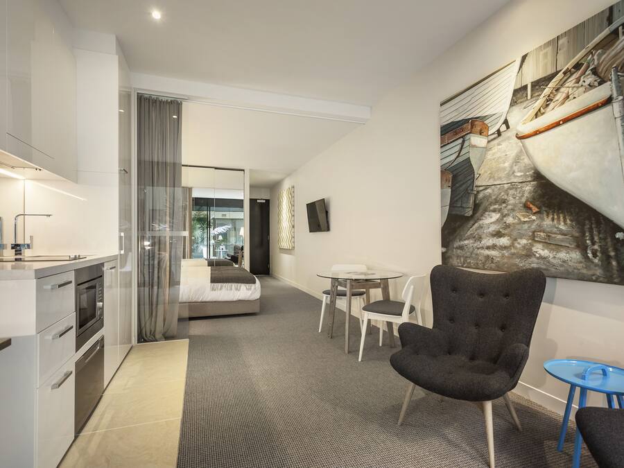 Ein modernes Hotelzimmer mit Küchenzeile, einem Bett, einem Essbereich und einem großen Kunstwerk an der Wand.
