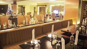 A restaurant with a long counter, cushioned seating, and a Christmas tree in the background. - Travello Manado (Manado)