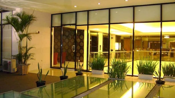 A modern indoor pool area with glass barriers and potted plants. - Travello Manado (Manado)