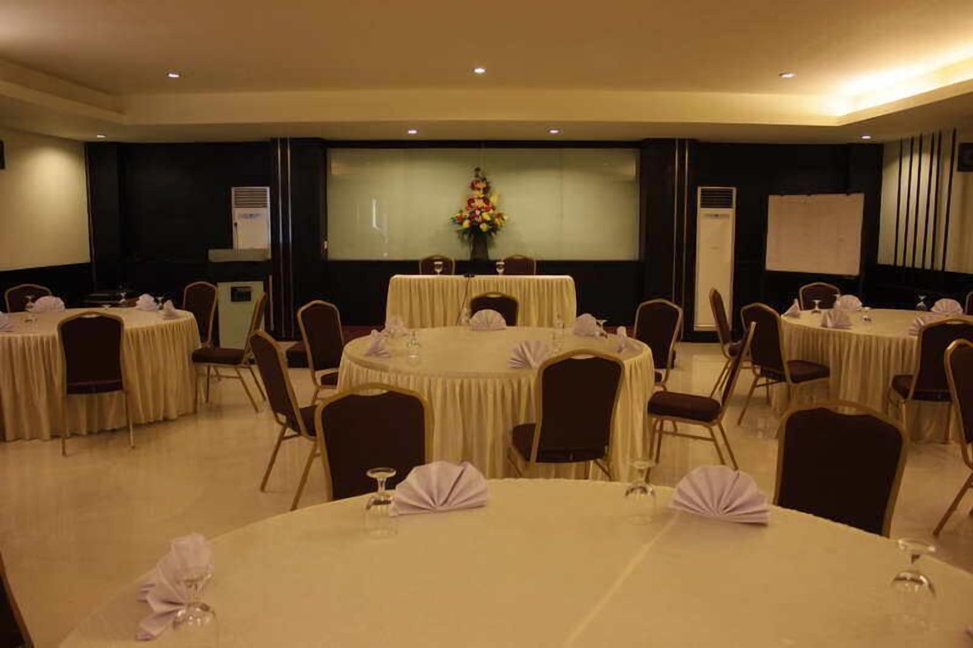 A conference room with multiple round tables, each with chairs and table settings.