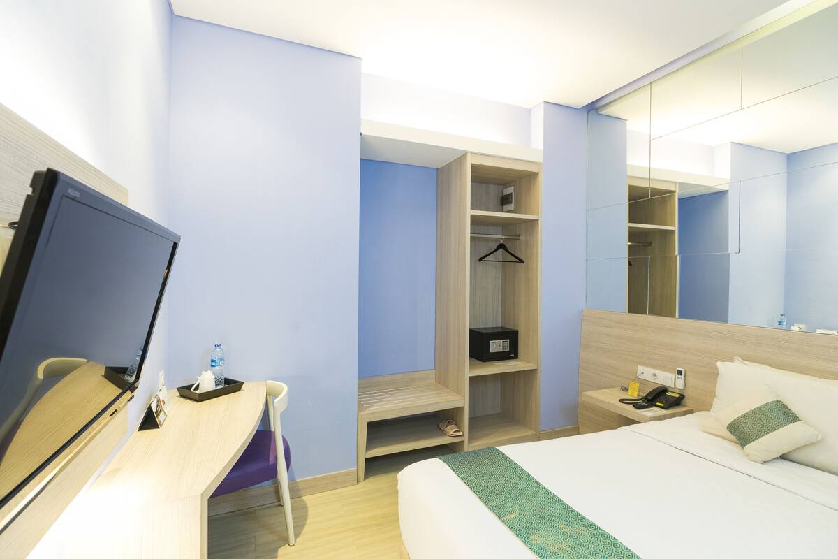 Een hotelkamer met een bed, een bureau, een kledingkast en een spiegel.