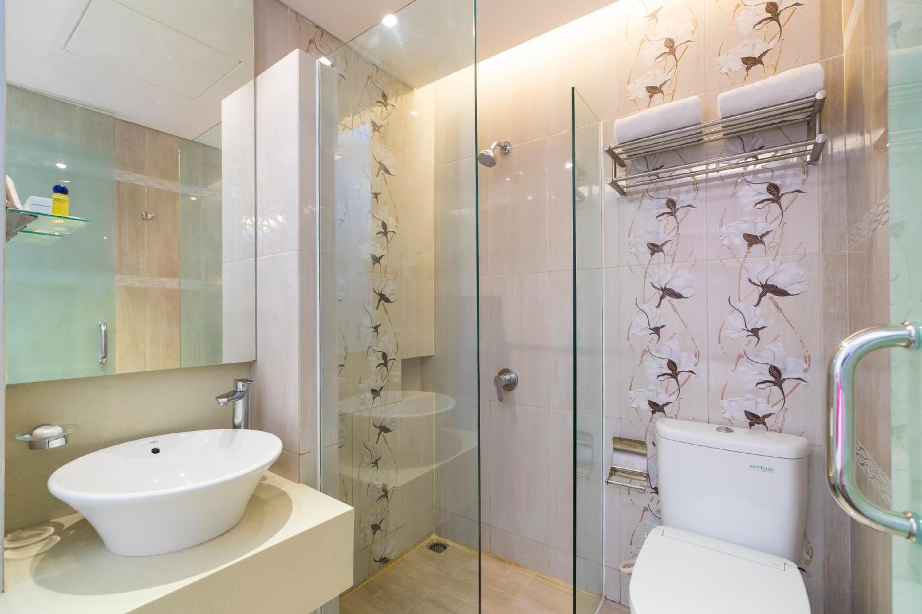 A modern bathroom with a glass-enclosed shower, a white sink, and a toilet.
