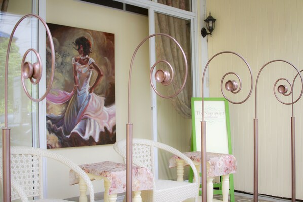 A room with wicker chairs, a painting on the wall, and a green sign.