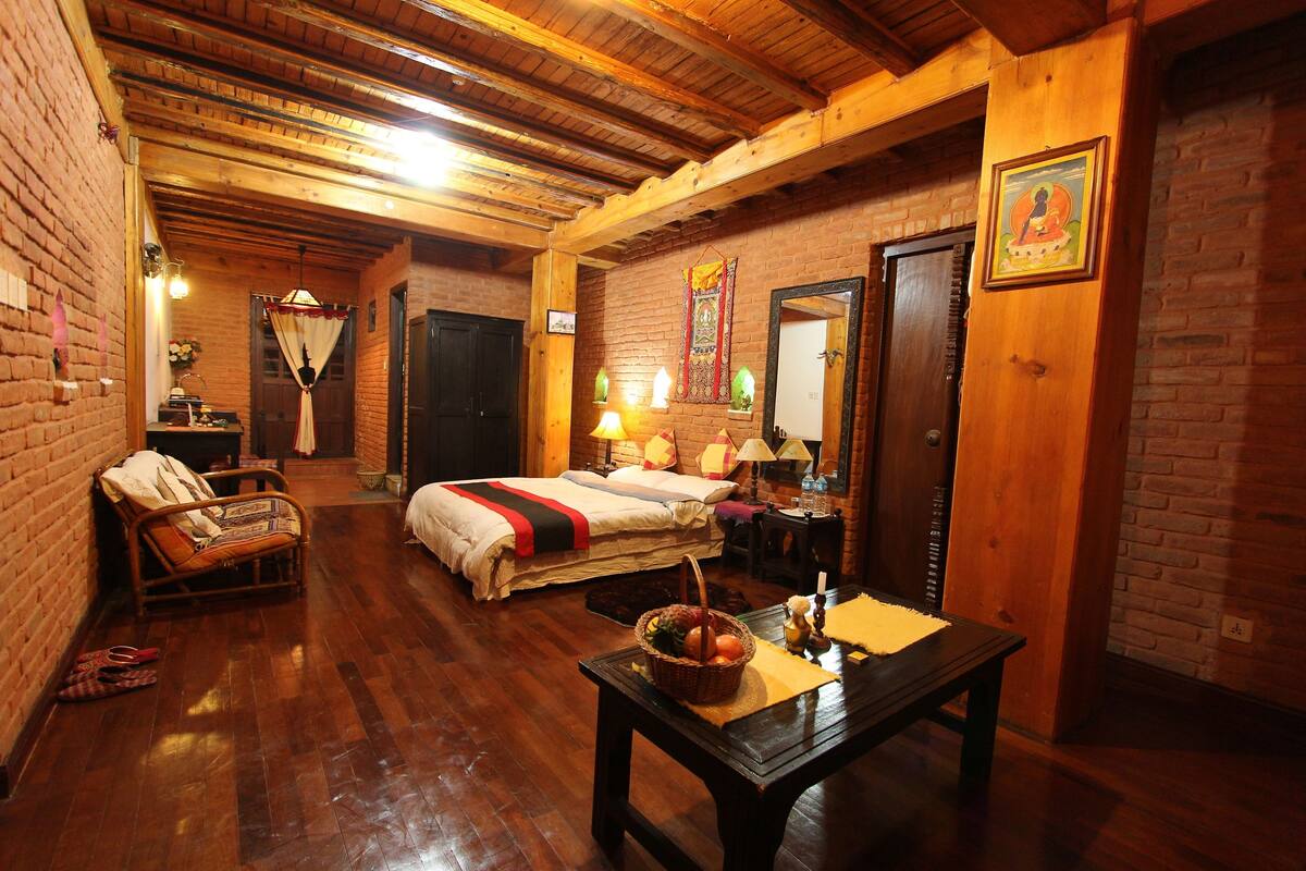 Een kamer met houten vloer, een bed, een tafel met een mand en een stoel.