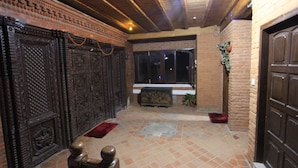 A hallway with ornate wooden doors, a tiled floor, and a window with a view of the night sky. - World Heritage Hotel & Aparments (Kathmandu)