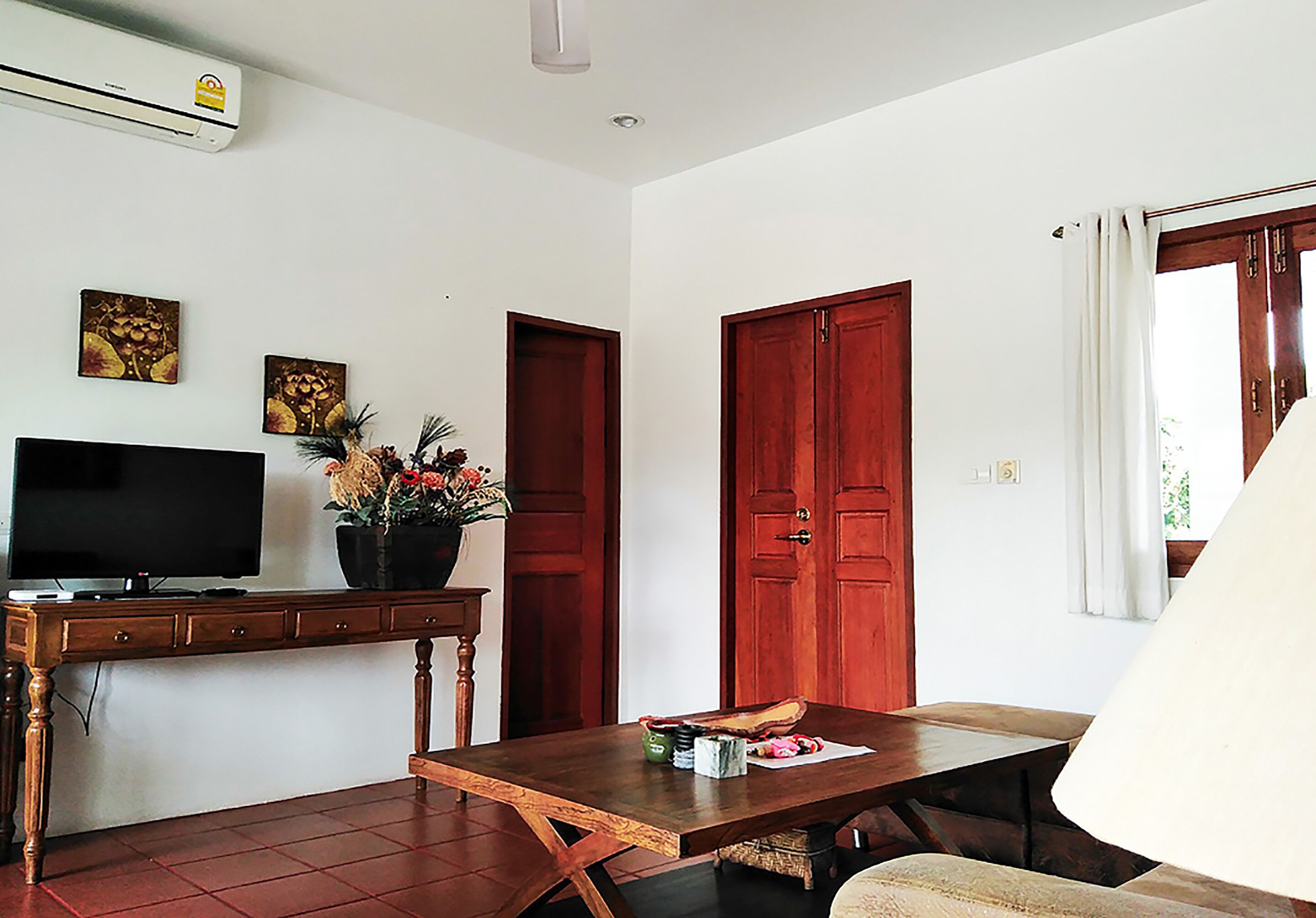 A living room with a TV, wooden furniture, a table with items, and a door.