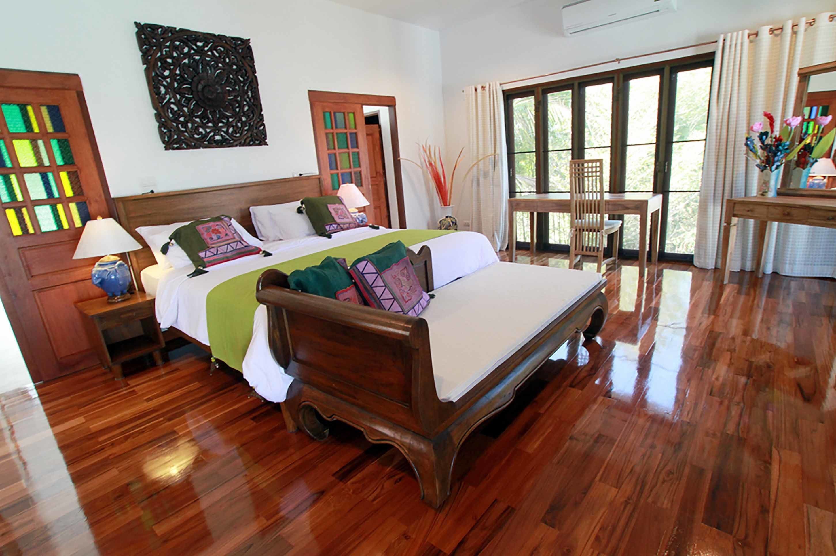 Un dormitorio amplio con una cama grande, piso de madera y vistas al exterior a través de un ventanal.