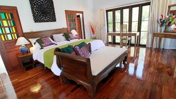 Un dormitorio amplio con una cama grande, piso de madera y vistas al exterior a través de un ventanal.