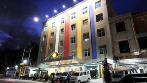A multi-story hotel with a brightly lit facade, a parking area with several vehicles, and a sign indicating the hotel's name. - Paramita Hotel (Pekanbaru)
