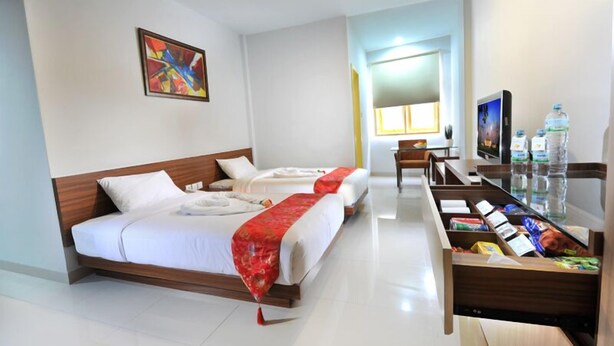 A hotel room with two beds, a TV, a desk with a computer, and a window. - Paramita Hotel (Pekanbaru)
