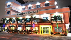 A multi-story building with a sign reading "Gaja Hotel." There are outdoor seating areas with umbrellas and palm trees. - Gaja Hotel (Pekanbaru)