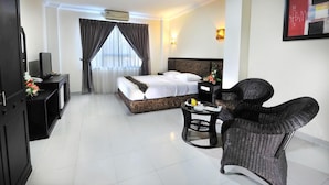 A hotel room with a bed, a television, a desk, a chair, and a window with curtains. - Gaja Hotel (Pekanbaru)