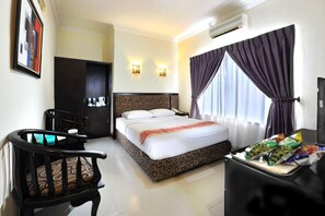 A hotel room with a bed, a desk, a chair, and a window with curtains. - Gaja Hotel (Pekanbaru)