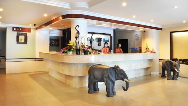 A reception area with a curved counter, two receptionists, and two elephant statues. - Gaja Hotel (Pekanbaru)