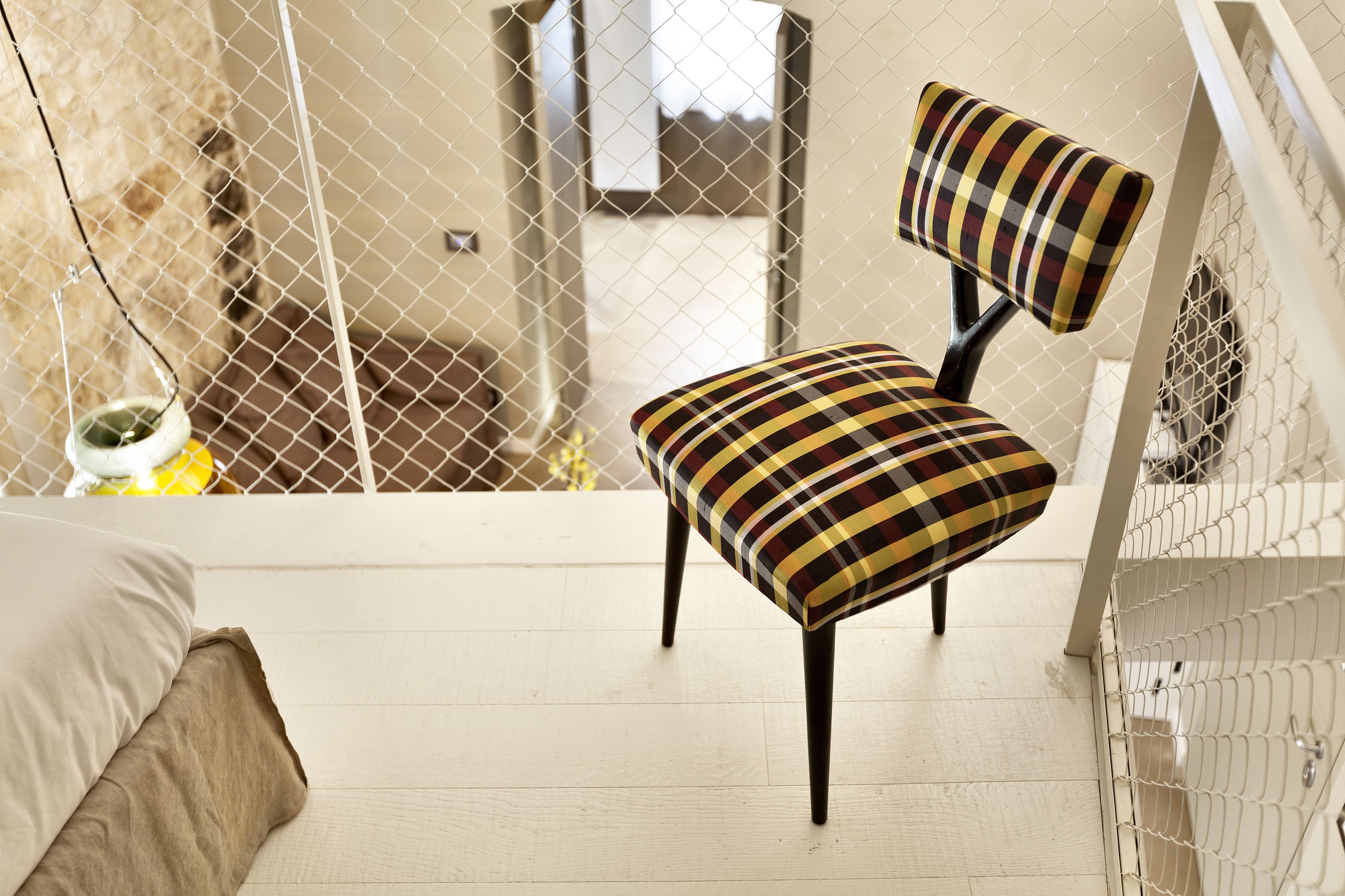A room with a bed, a chair, and a small table with a plant.