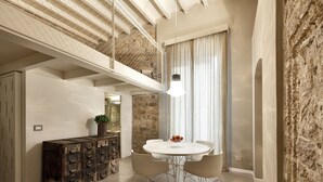 A dining area with a round table, four chairs, a plant, and a vintage cabinet. - Palazzo Calò (Bari)
