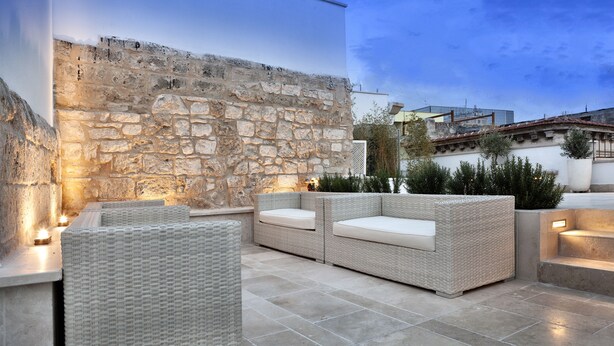 An outdoor seating area with wicker furniture and stone walls. - Palazzo Calò (Bari)