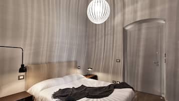 Ein modernes Schlafzimmer mit einem großen Bett, einem Nachttisch mit Lampe, einer Pendelleuchte und einer Tür.