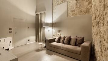 A modern living room with a beige sofa, a lamp, and a stone accent wall.