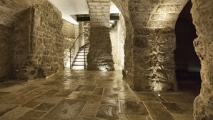 A stone corridor with a staircase leading to a higher level, featuring arched ceilings and a tiled floor. - Palazzo Calò (Bari)