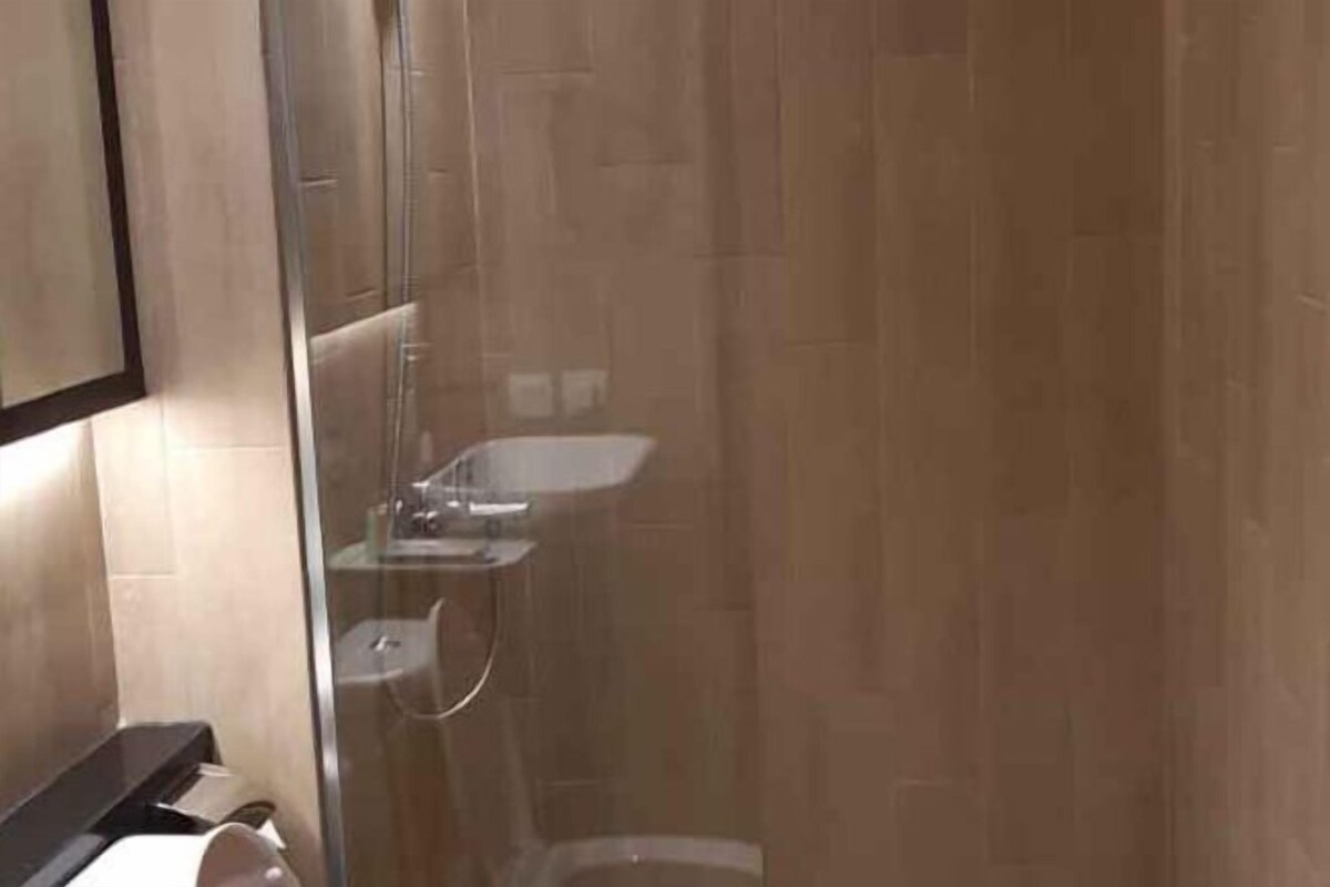 Une salle de bain moderne avec une douche à parois de verre, un lavabo apparent et des toilettes.