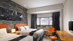 Hotelkamer met twee bedden, een houten bureau, een stoel, een televisie en een groot raam met uitzicht op de stad.