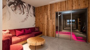 A modern interior with a red sofa, a wooden coffee table, and a large wall mural. - Hotel Dorfer (Grossarl)