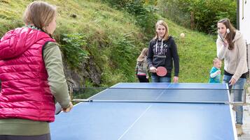 A group of people playing table tennis outdoors.