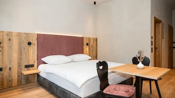 Een moderne slaapkamer met een bed, nachtkastje, stoel en een klein tafeltje met een vaas.