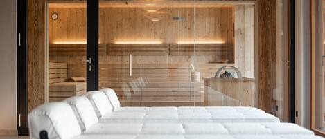 Quarto moderno com cama grande, painéis de madeira e divisória de vidro.