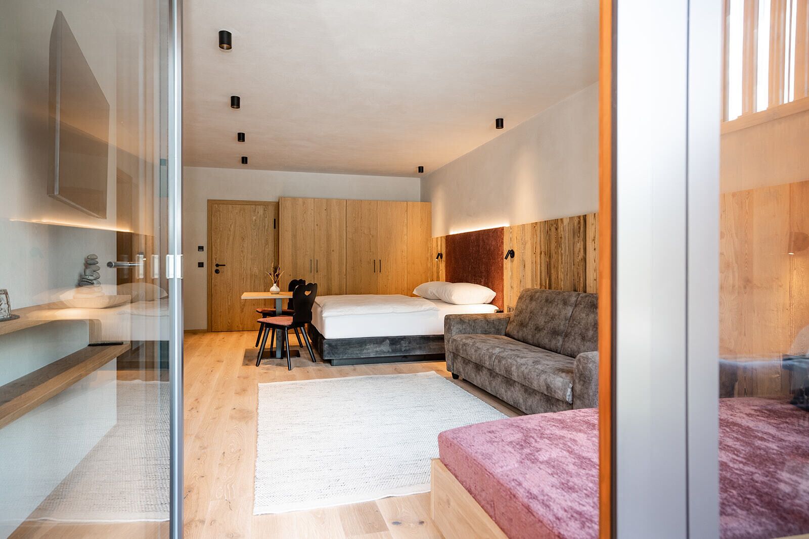 A modern bedroom with a bed, a sofa, a desk, and a chair.