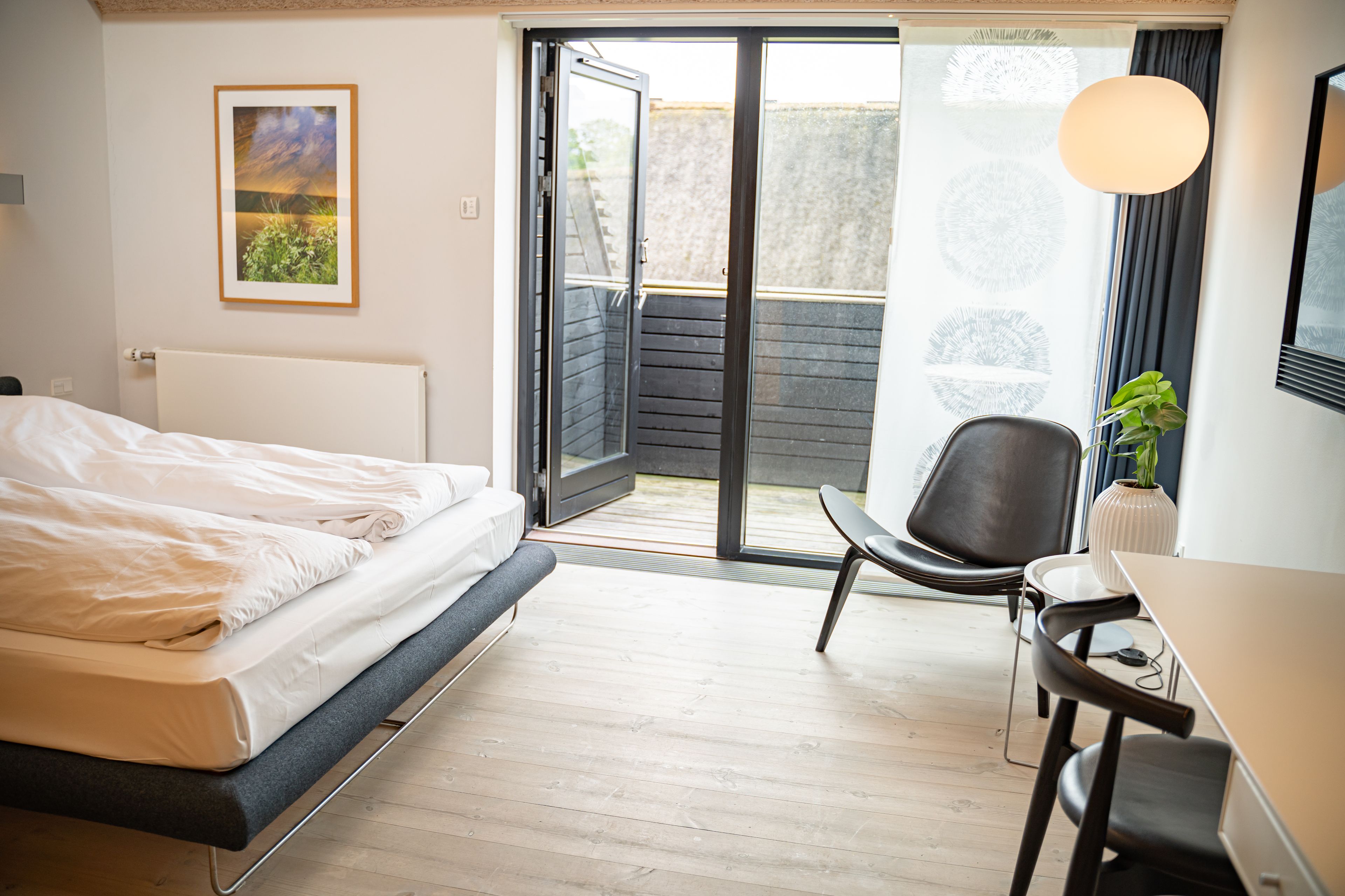 A modern hotel room with a bed, a desk, and a chair.