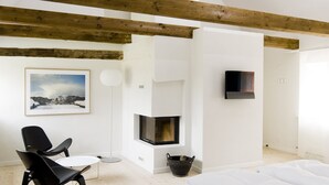 A modern room with exposed wooden beams, a fireplace, a framed picture, a TV, and a dining area. - Nørre Vosborg Herregård (Vemb)