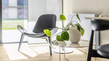 A modern room with a black chair, a small round table, and a potted plant.
