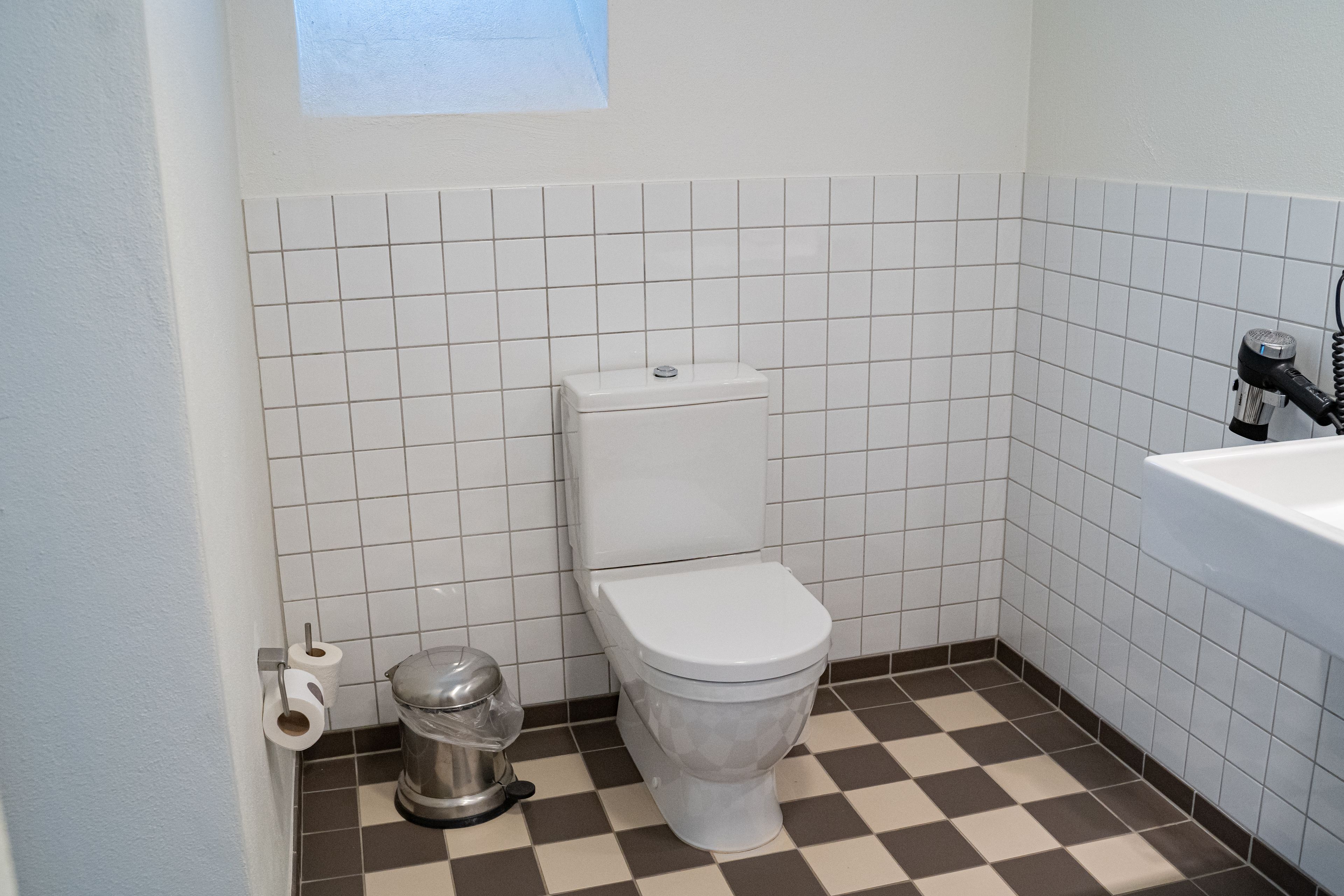 Ein kleines Badezimmer mit Toilette, Mülleimer und Badewanne.
