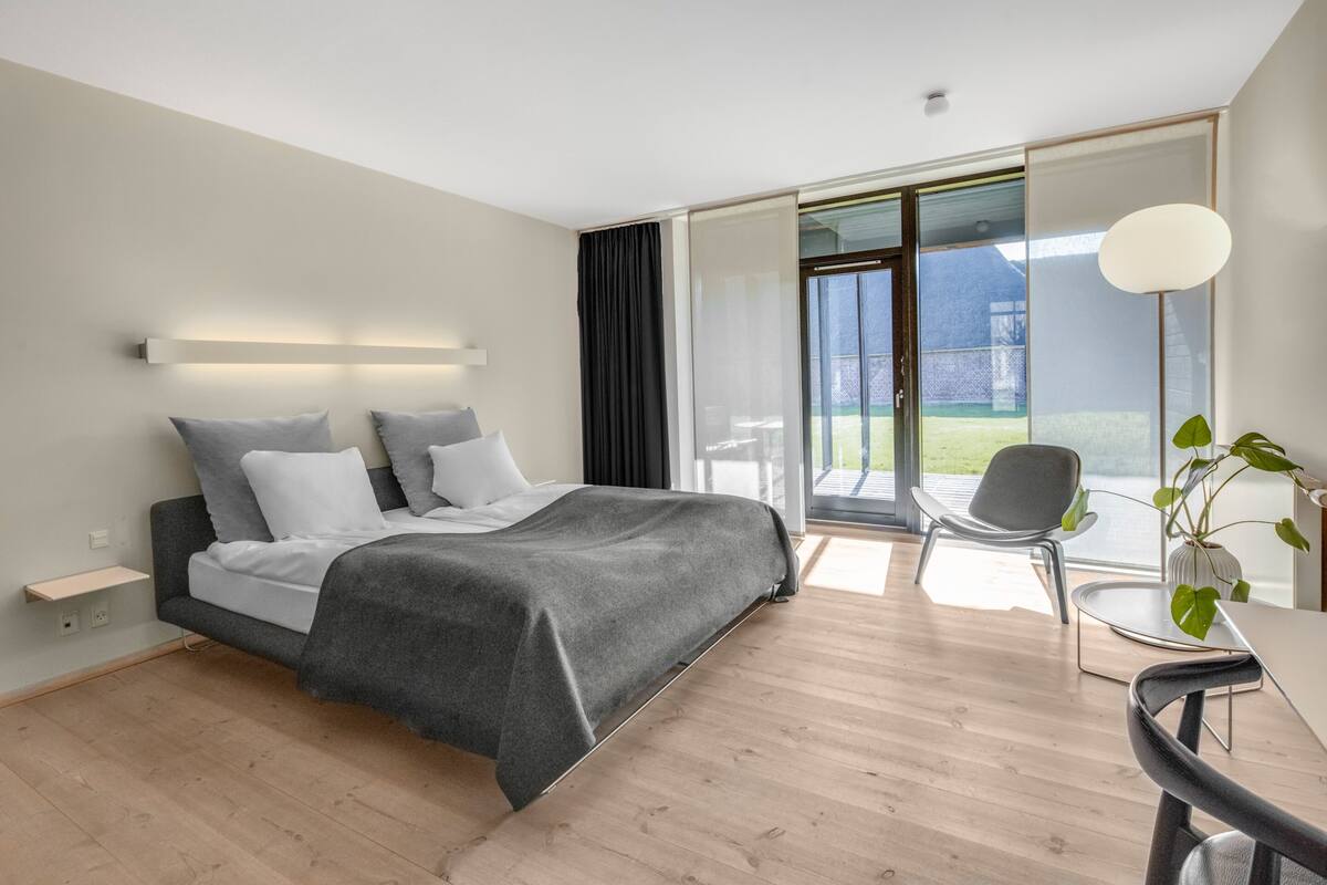 Une chambre moderne avec un grand lit, un bureau et une vue sur l’extérieur.