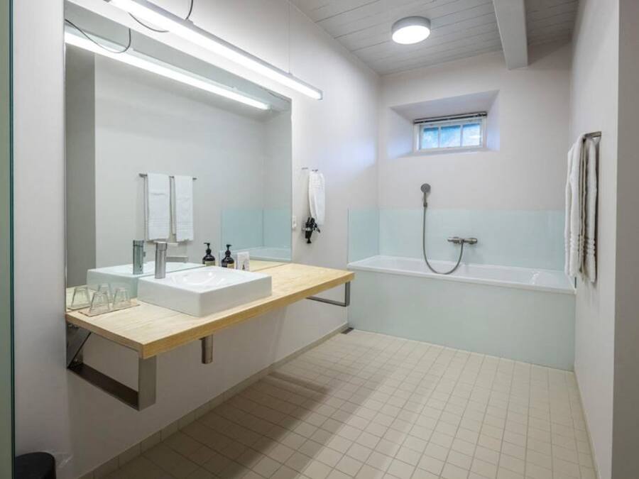 Uma casa de banho moderna com um espelho grande, duas pias, uma banheira e um chuveiro.