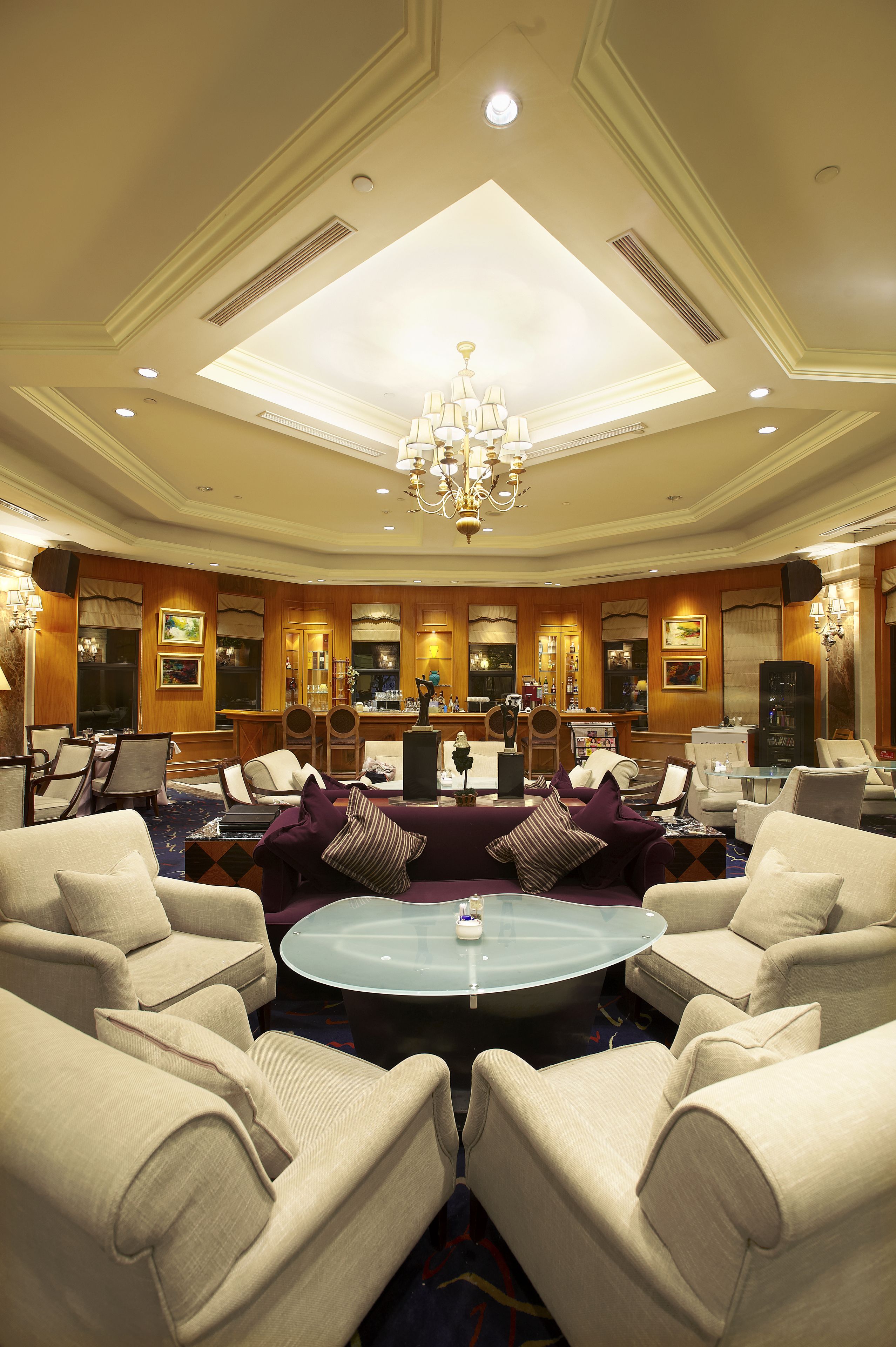 A spacious hotel lobby with a high ceiling, chandeliers, and comfortable seating areas.